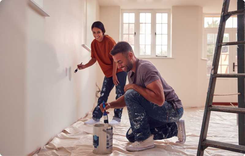 Man and woman painting a wall white