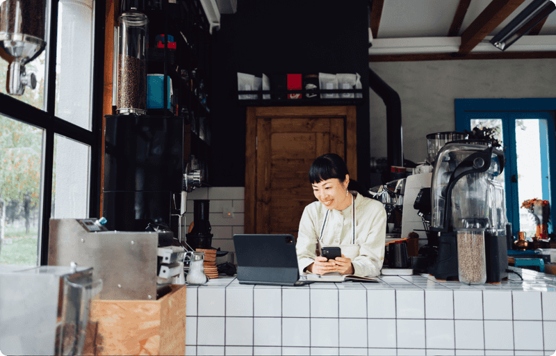 Woman looking at her phone while working at her coffee shop