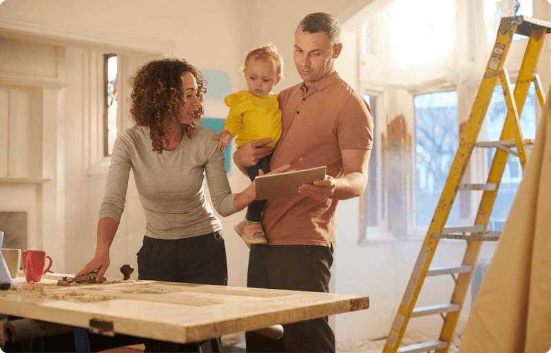 A family decorating front room next to a ladder