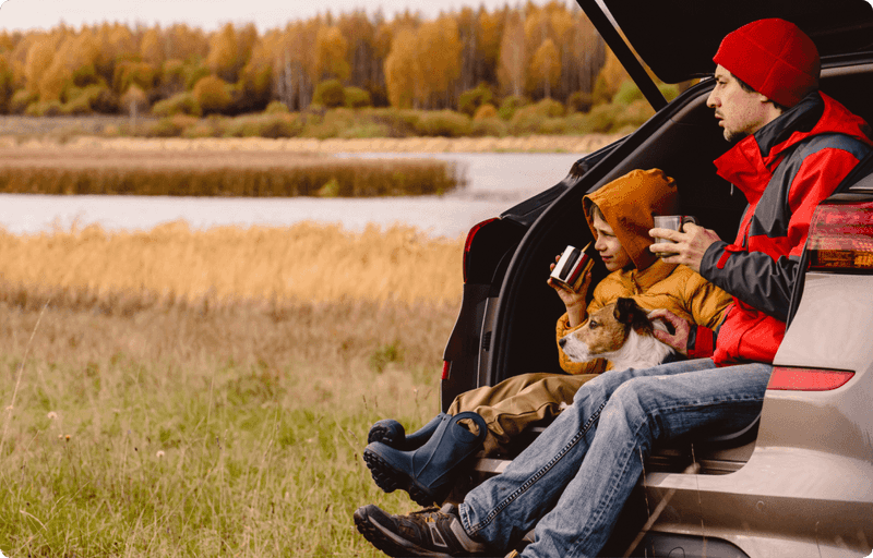 Father and his son sitting in the car boot